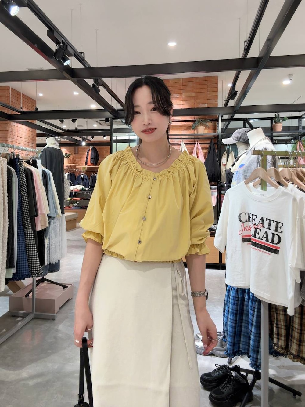 ホワイト系のスカート、ブラック系のトートバッグ、シルバー系のサンダルを着用したレディースの春コーディネートの4枚目の写真