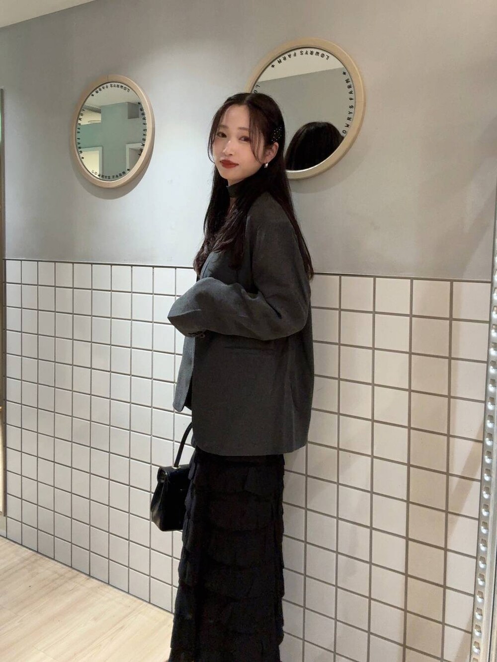 ブラック系のタンクトップ、グレー系のテーラードジャケット、ブラック系のボストンバッグを着用したレディースの秋コーディネートの3枚目の写真