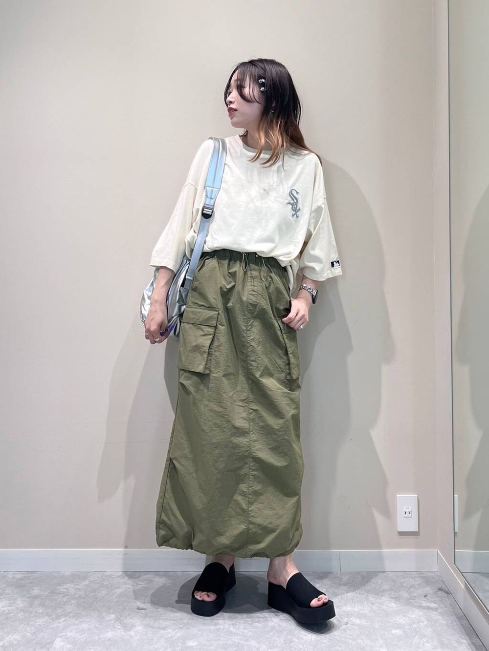 ブラック系のサンダル、シルバー系のバックパック/リュック、グリーン系のスカートを着用したレディースの春コーディネートの3枚目の写真