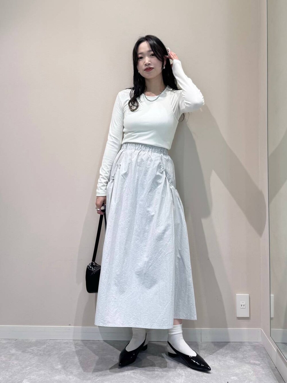 ブラック系のトートバッグ、ホワイト系のTシャツ/カットソー、ブラック系のパンプスを着用したレディースの春コーディネートの2枚目の写真