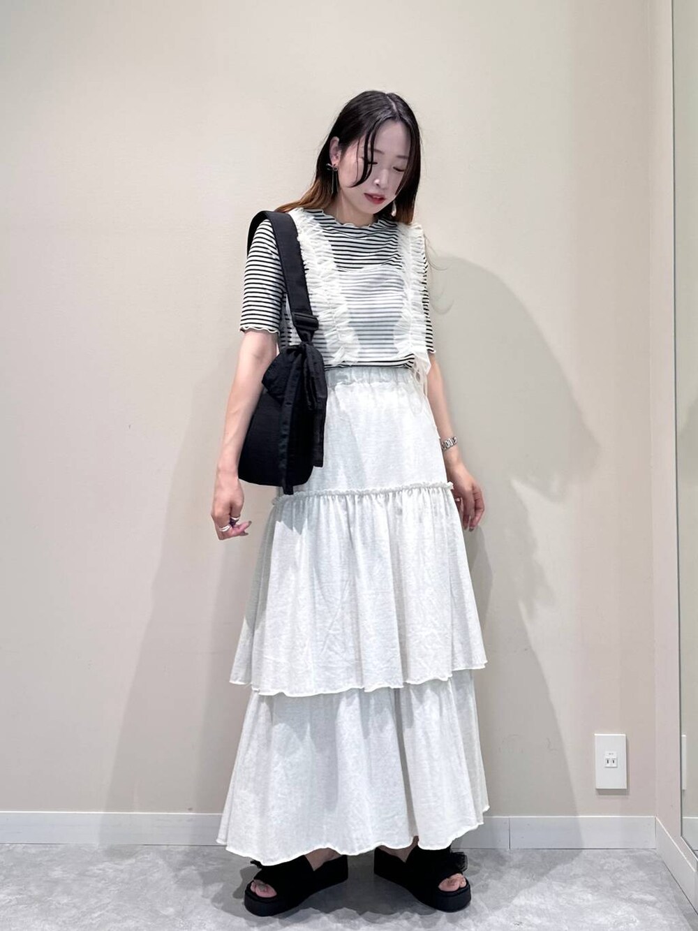 ブラック系のサンダル、ブラック系のショルダーバッグ、ホワイト系のTシャツ/カットソーを着用したレディースの夏コーディネートの2枚目の写真