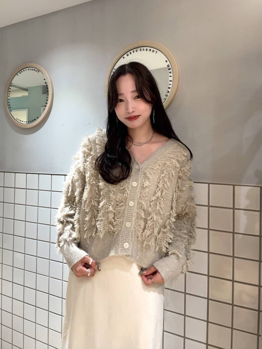 ホワイト系のスカート、ベージュ系のカーディガン/ボレロ、ブラック系のボストンバッグを着用したレディースの秋コーディネートの4枚目の写真