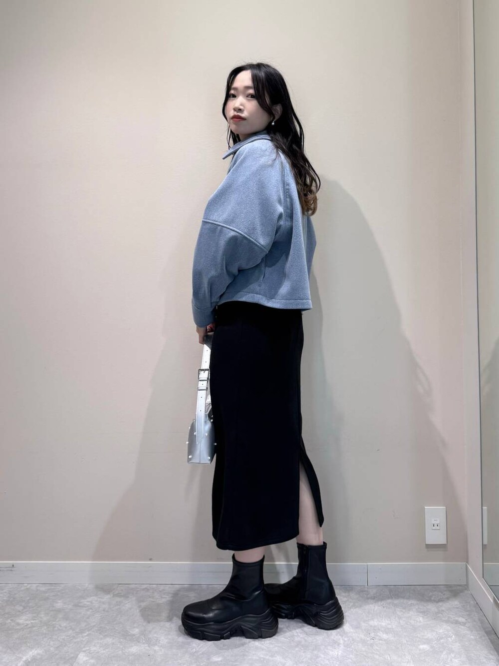 ブラック系のブーツ、シルバー系のショルダーバッグ、ブラック系のワンピースを着用したレディースの冬コーディネートの3枚目の写真