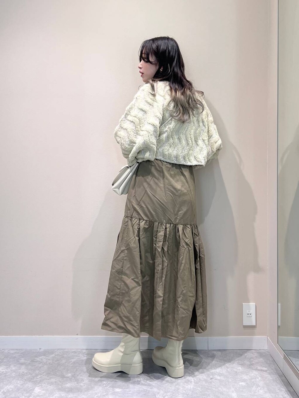 ホワイト系のショルダーバッグ、ホワイト系のブーツ、ホワイト系のニット/セーターを着用したレディースの冬コーディネートの4枚目の写真