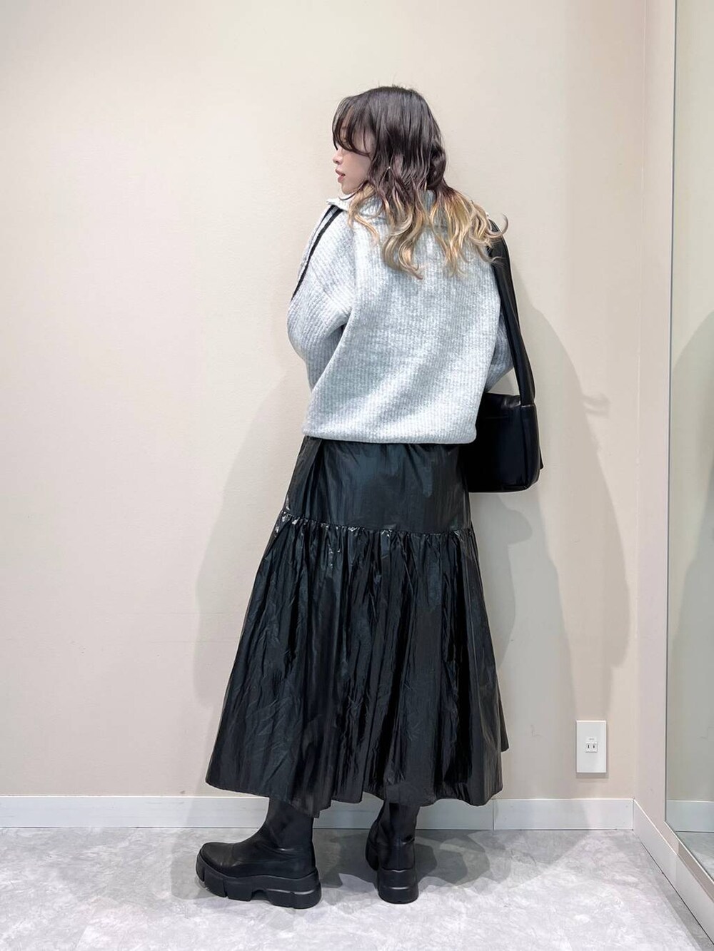 ブラック系のブーツ、ブラック系のショルダーバッグ、ブラック系のスカートを着用したレディースの冬コーディネートの4枚目の写真