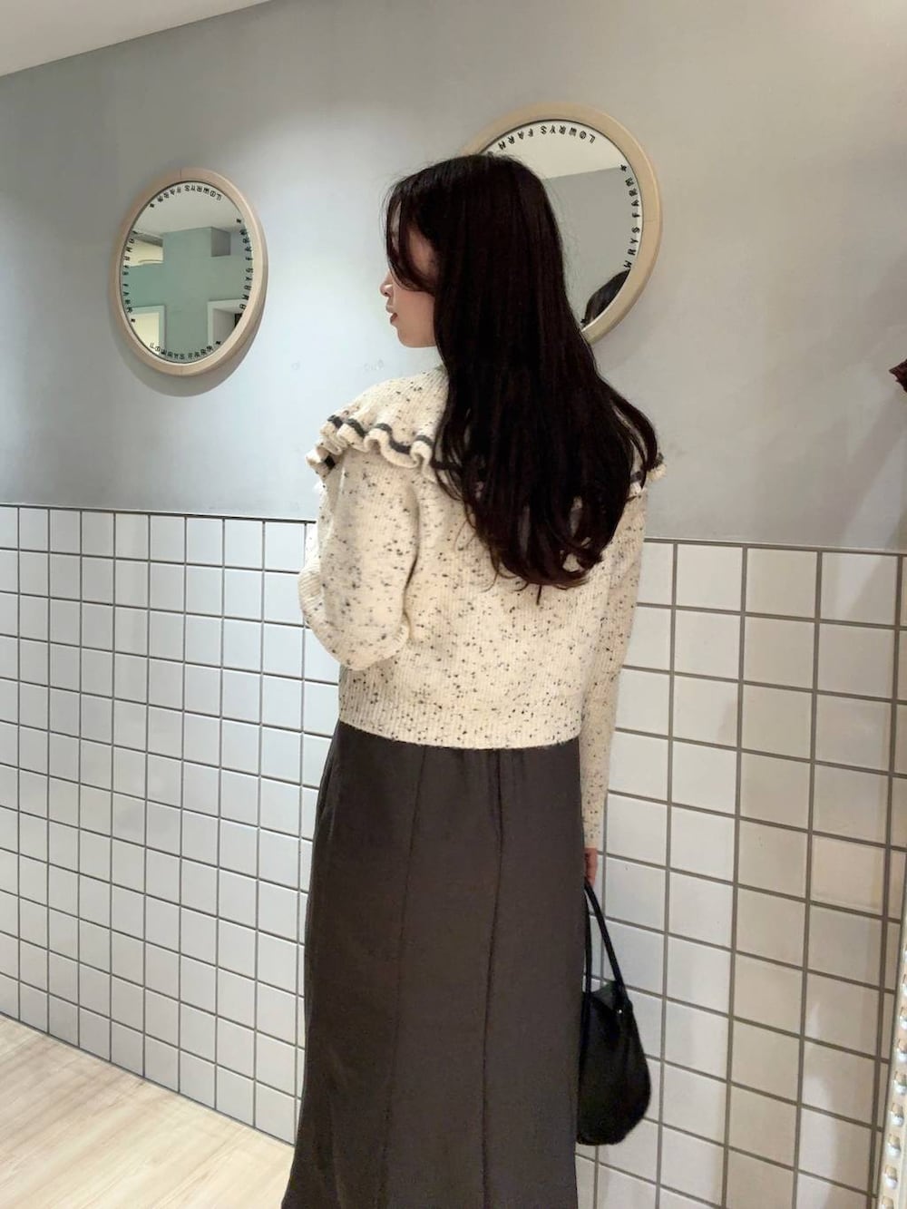 ブラック系のショルダーバッグ、グレー系のスカート、ベージュ系のニット/セーターを着用したレディースの秋コーディネートの2枚目の写真