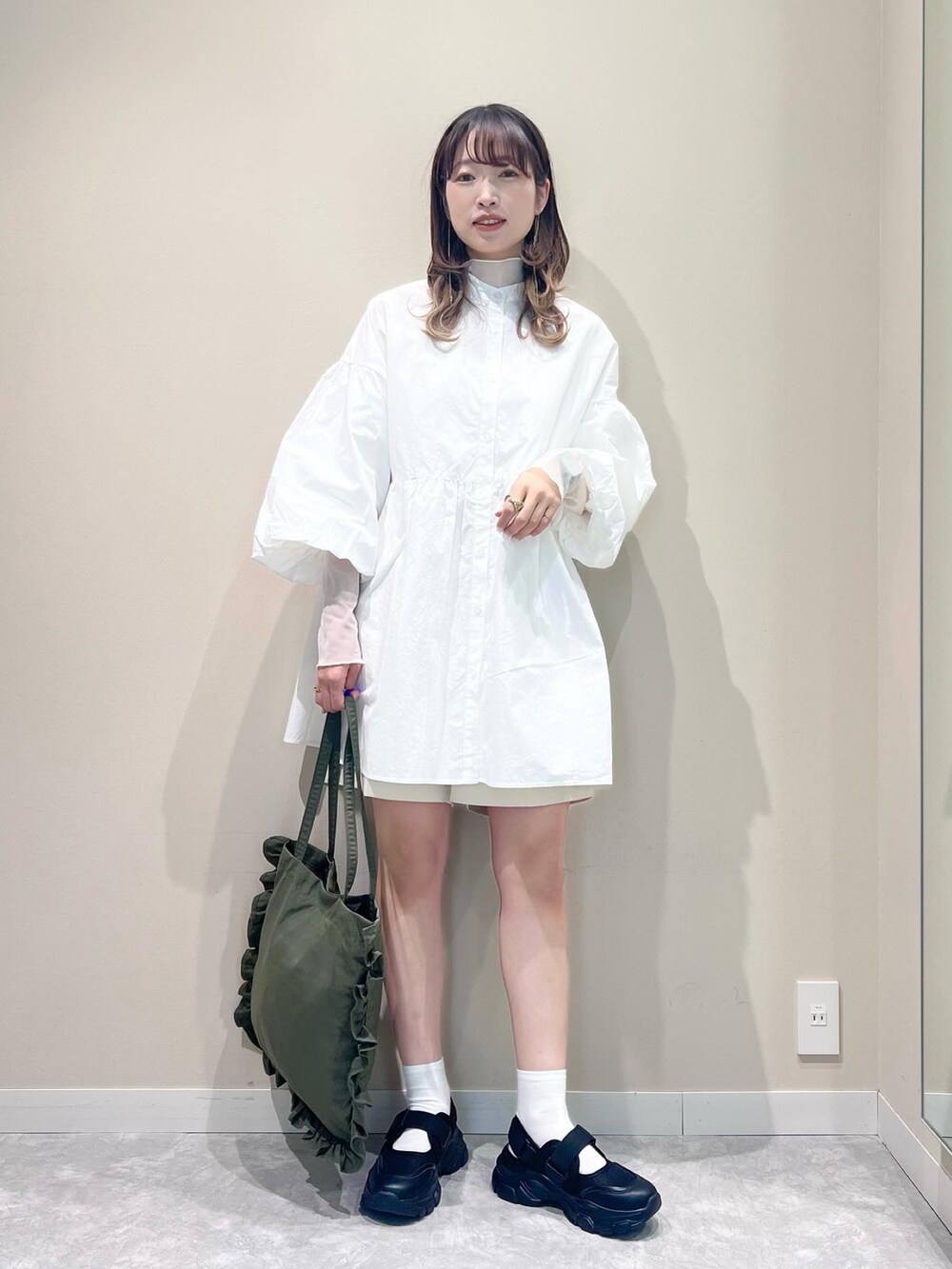 ホワイト系のトップス、グリーン系のトートバッグ、ホワイト系のパンツを着用したレディースの春コーディネートの2枚目の写真