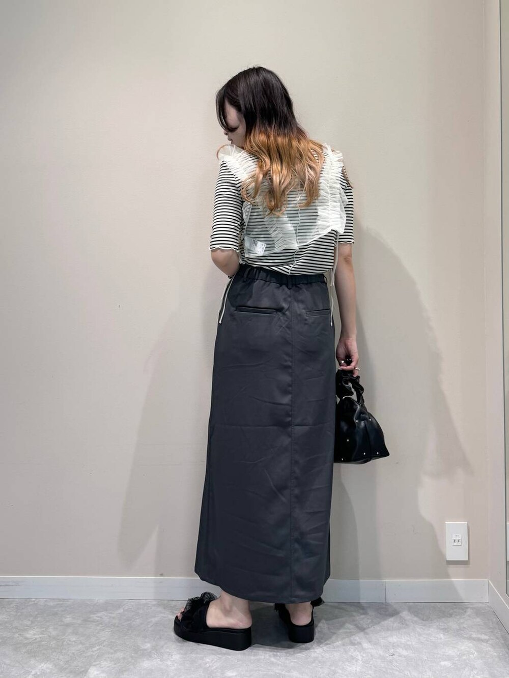 ブラック系のハンドバッグ、ブラック系のサンダル、ホワイト系のTシャツ/カットソーを着用したレディースの夏コーディネートの3枚目の写真