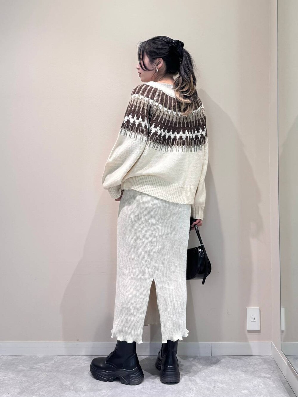 ブラック系のショルダーバッグ、ホワイト系のTシャツ/カットソー、ホワイト系のスカートを着用したレディースの冬コーディネートの3枚目の写真