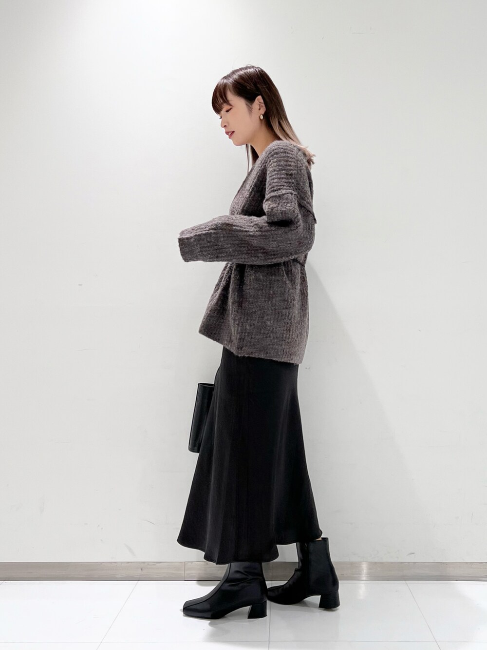 ブラック系のショルダーバッグ、ブラック系のスカート、ブラック系のブーツを着用したレディースの冬コーディネートの3枚目の写真