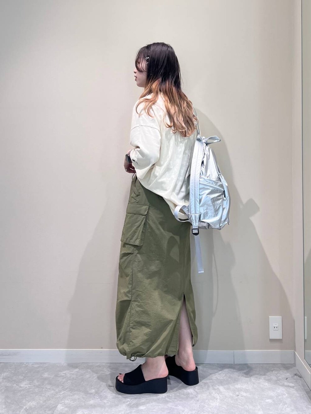 ブラック系のサンダル、シルバー系のバックパック/リュック、グリーン系のスカートを着用したレディースの春コーディネートの2枚目の写真
