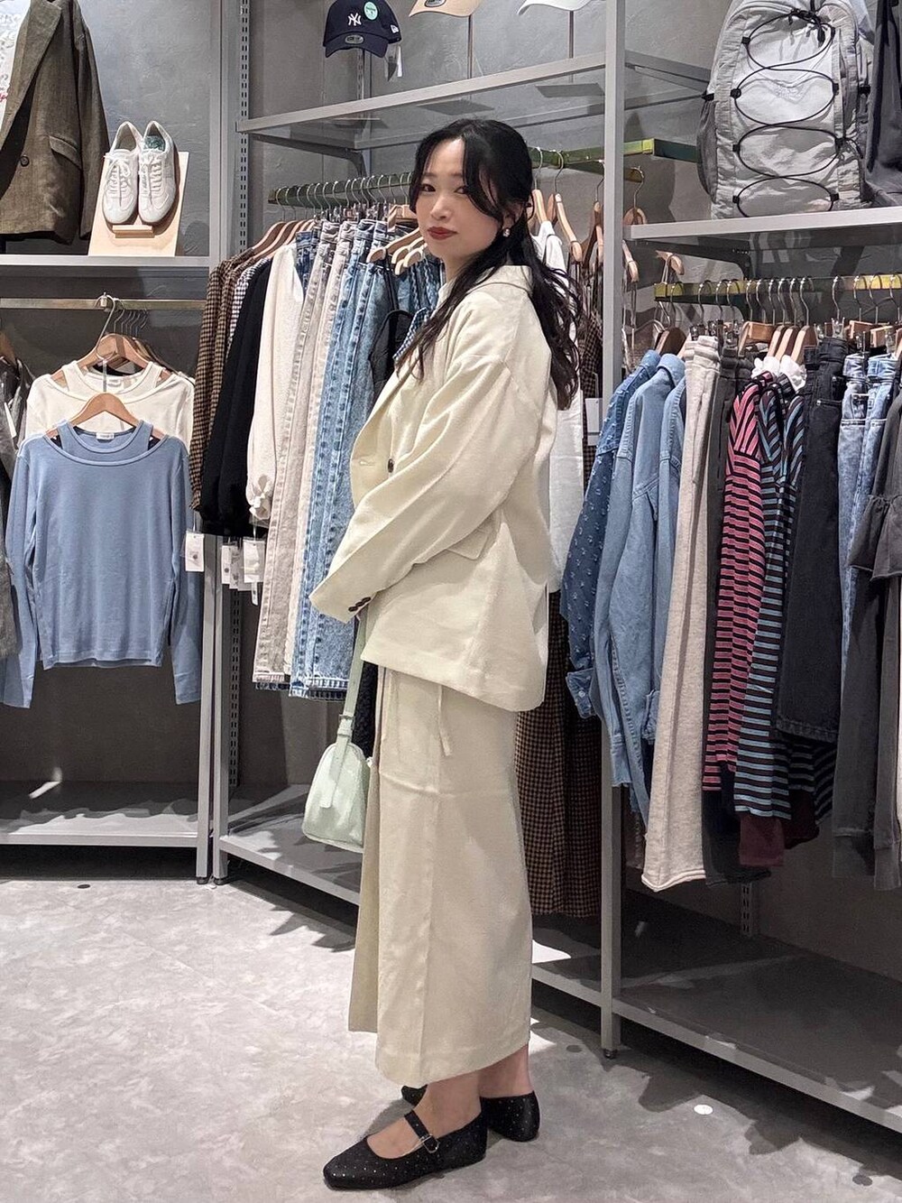 ホワイト系のスカート、ホワイト系のテーラードジャケット、グリーン系のトートバッグを着用したレディースの春コーディネートの2枚目の写真