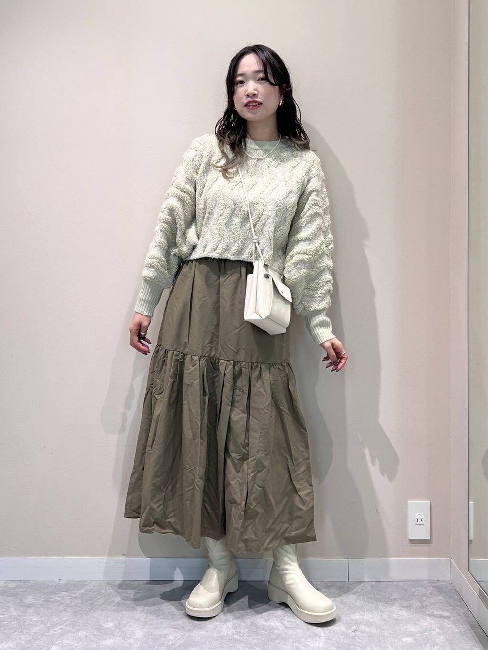 ホワイト系のショルダーバッグ、ホワイト系のブーツ、ホワイト系のニット/セーターを着用したレディースの冬コーディネートの5枚目の写真