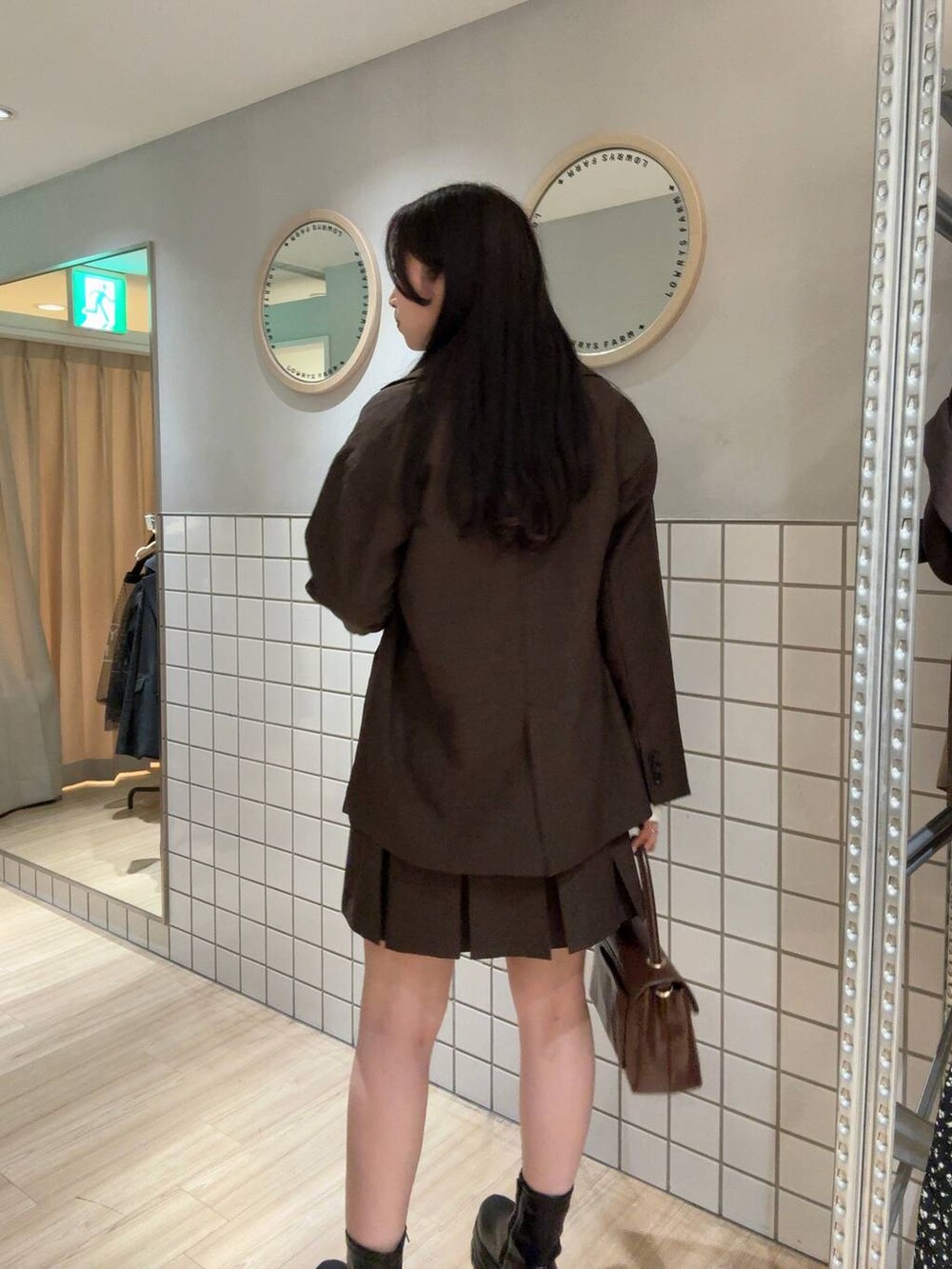 ブラック系のブーツ、ブラウン系のテーラードジャケット、ブラウン系のスカートを着用したレディースの秋コーディネートの2枚目の写真