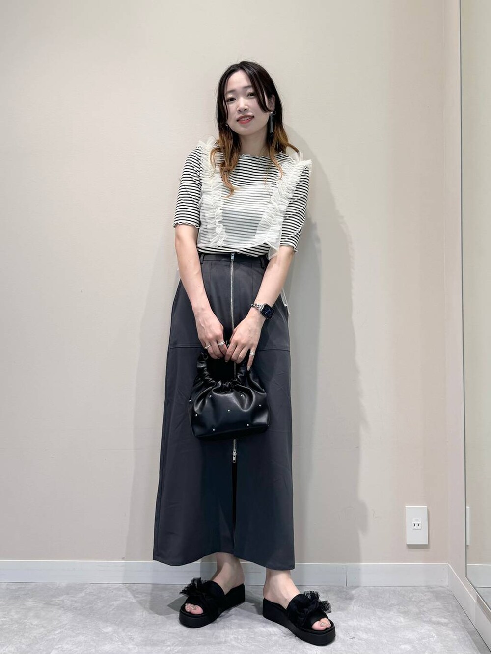 ブラック系のハンドバッグ、ブラック系のサンダル、ホワイト系のTシャツ/カットソーを着用したレディースの夏コーディネートの2枚目の写真