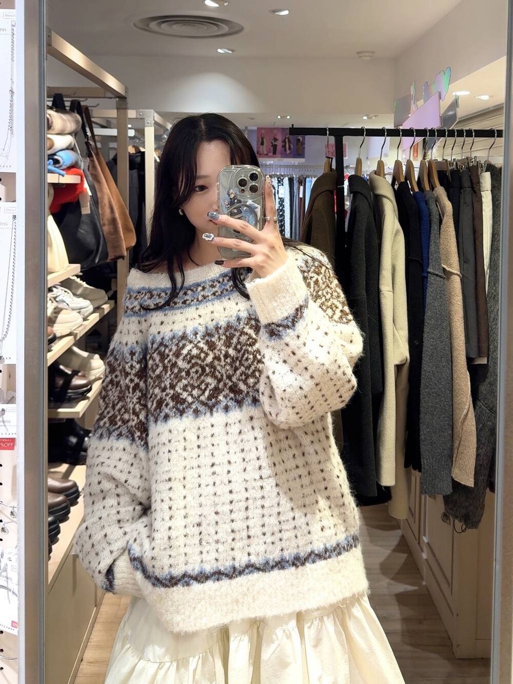 ホワイト系のニット/セーター、ホワイト系のスマホケース/カバーを着用したレディースの冬コーディネートの2枚目の写真