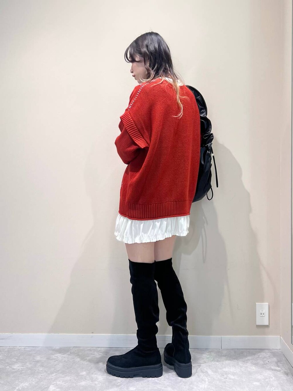レッド系のTシャツ/カットソー、ブラック系のショルダーバッグ、ブラック系のブーツを着用したレディースの冬コーディネートの4枚目の写真