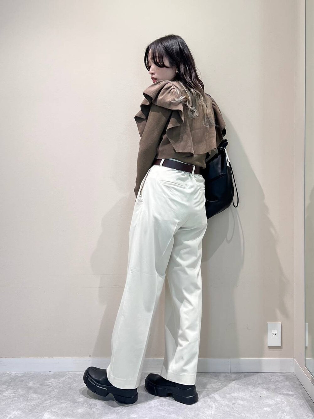 ブラック系のショルダーバッグ、ブラック系のブーツ、ブラウン系のニット/セーターを着用したレディースの冬コーディネートの2枚目の写真