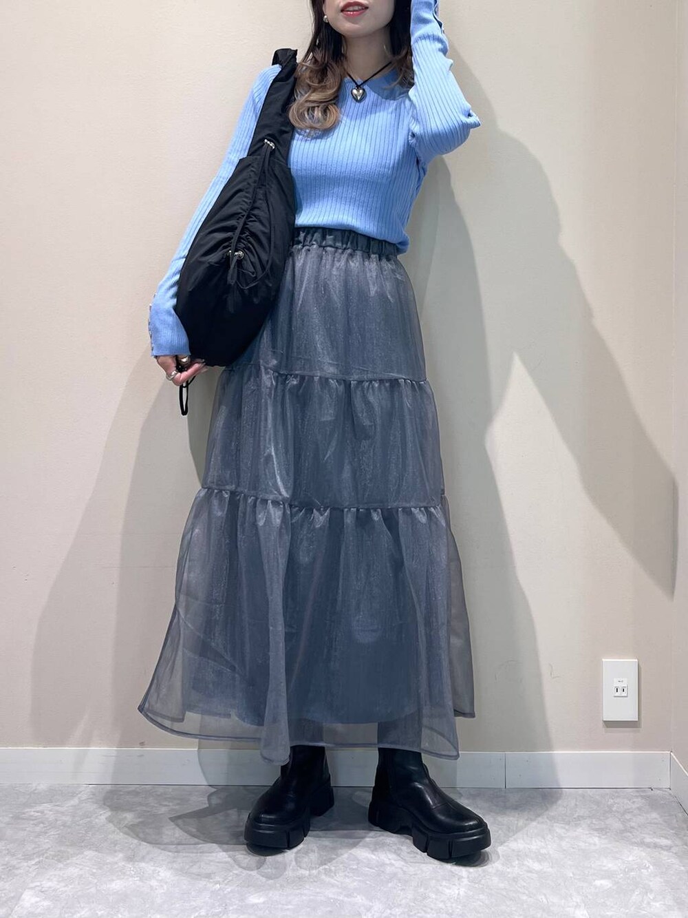 ブラック系のブーツ、ブラック系のショルダーバッグ、ブルー系のニット/セーターを着用したレディースの冬コーディネートの3枚目の写真