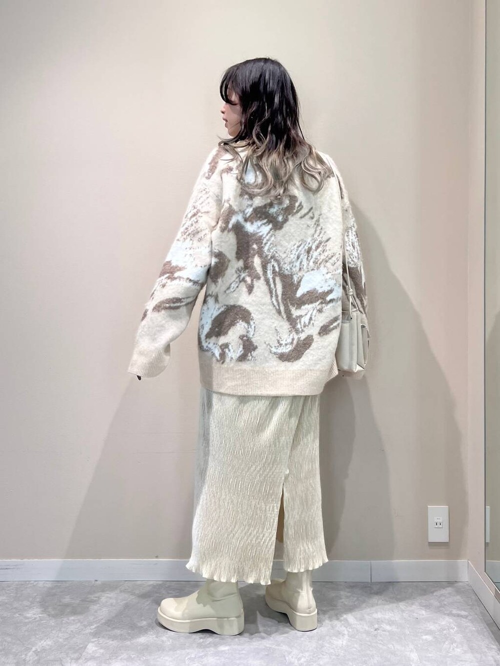 ホワイト系のショルダーバッグ、ホワイト系のTシャツ/カットソー、ホワイト系のブーツを着用したレディースの冬コーディネートの2枚目の写真