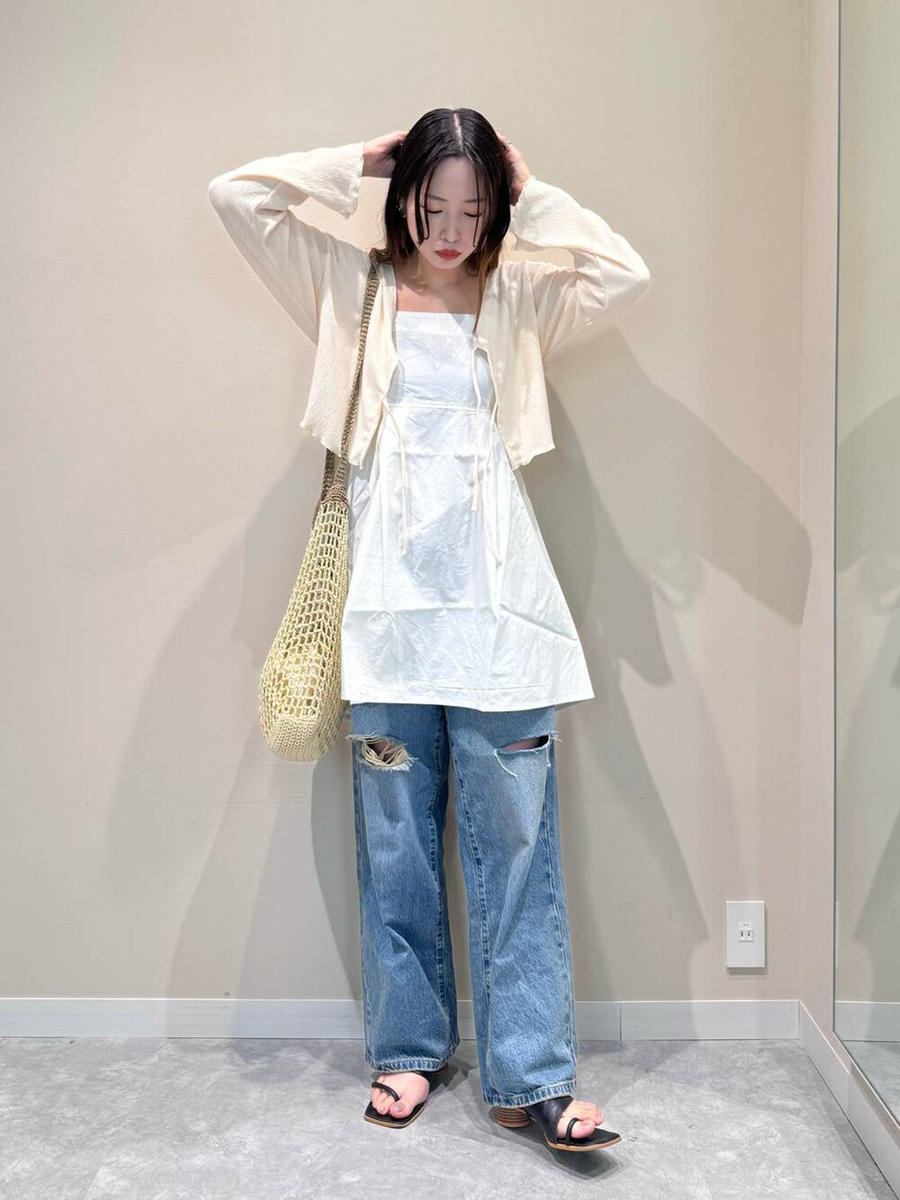 ベージュ系のショルダーバッグ、ホワイト系のシャツ/ブラウス、ブルー系のデニムパンツを着用したレディースの夏コーディネートの3枚目の写真