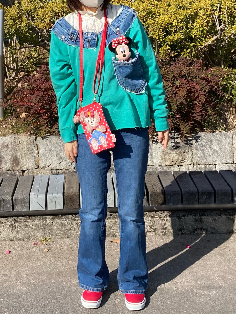 グリーン系のスウェット、ブルー系のデニムパンツ、レッド系のスニーカーを着用したレディースの冬コーディネートの3枚目の写真