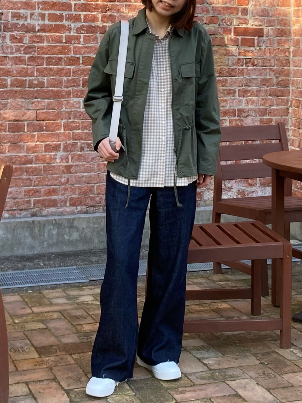 グリーン系のミリタリージャケット、ベージュ系のシャツ/ブラウス、ブルー系のデニムパンツを着用したレディースの春コーディネートの2枚目の写真