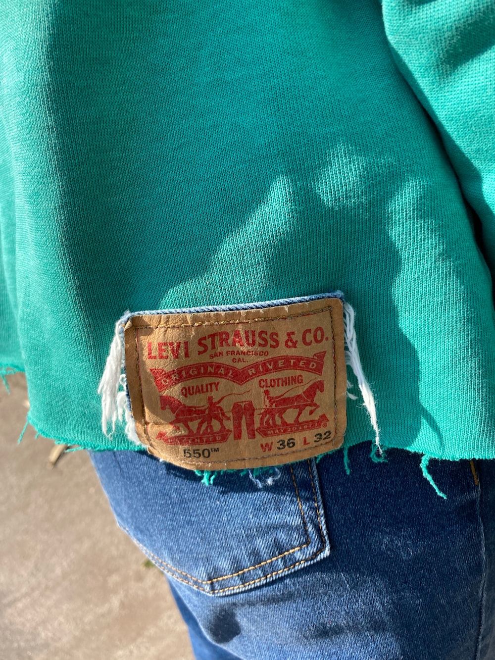 グリーン系のスウェット、ブルー系のデニムパンツ、レッド系のスニーカーを着用したレディースの冬コーディネートの5枚目の写真