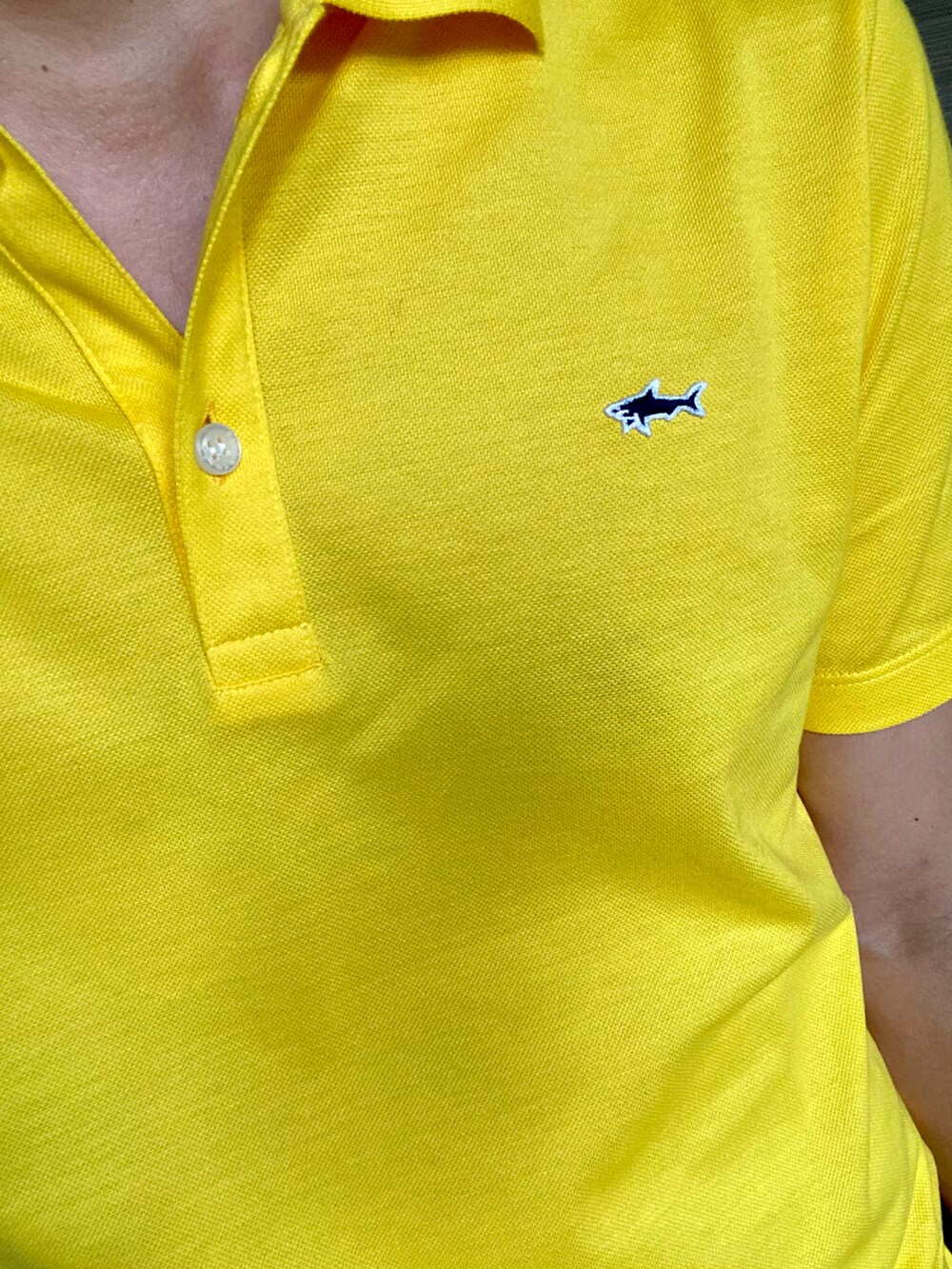 イエロー系のポロシャツ、ブラック系のチノパンツ、ホワイト系のスニーカーを着用したメンズの夏コーディネートの2枚目の写真