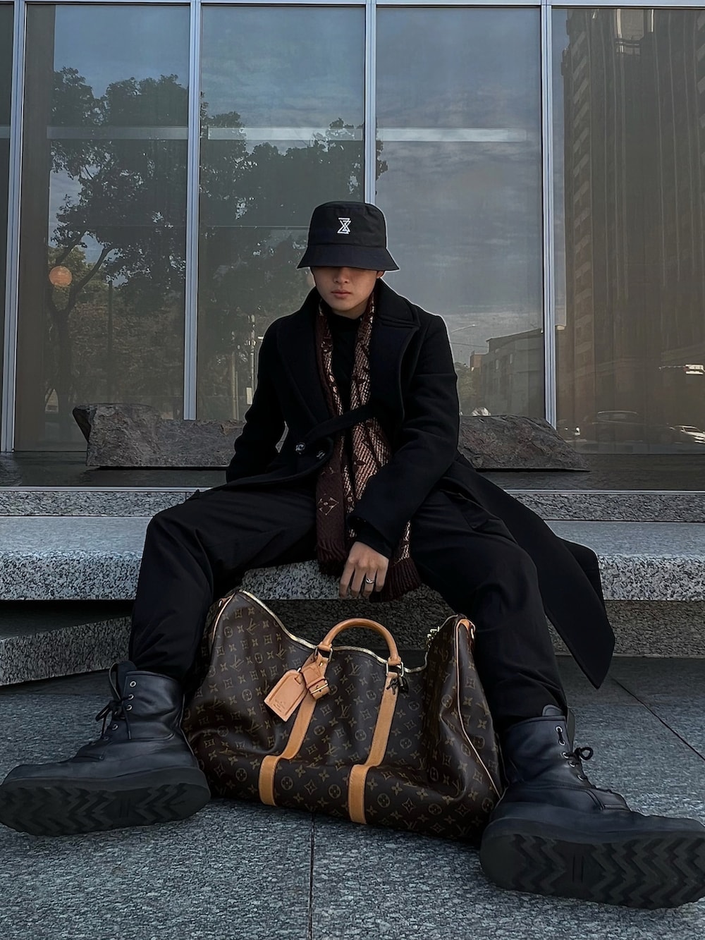 ブラウン系のスーツケース/キャリーバッグ、ブラック系のダウンジャケット/コートを着用したメンズの冬コーディネートの2枚目の写真