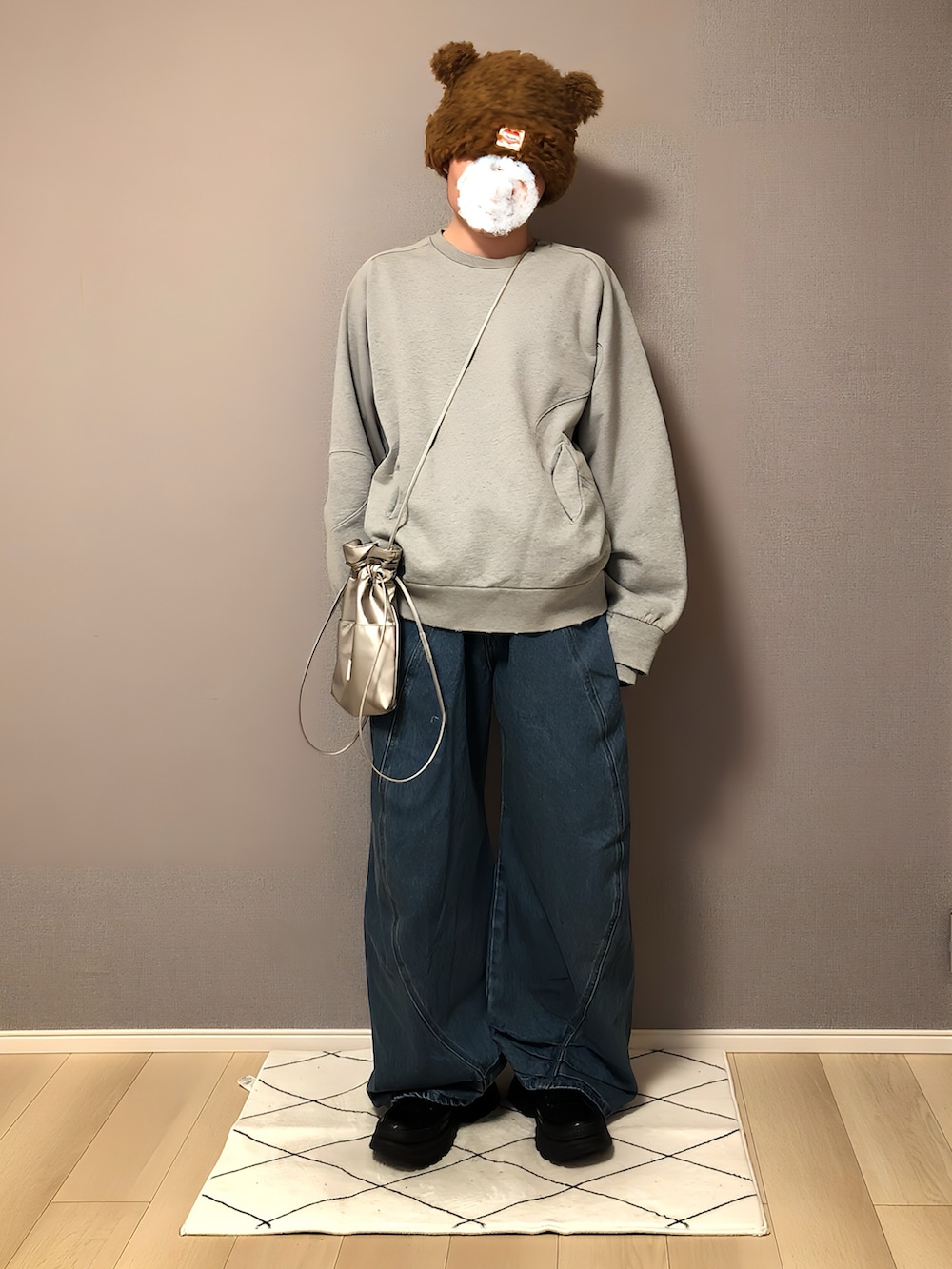 グレー系のスウェット、ブルー系のデニムパンツ、シルバー系のショルダーバッグを着用したメンズの冬コーディネートの2枚目の写真