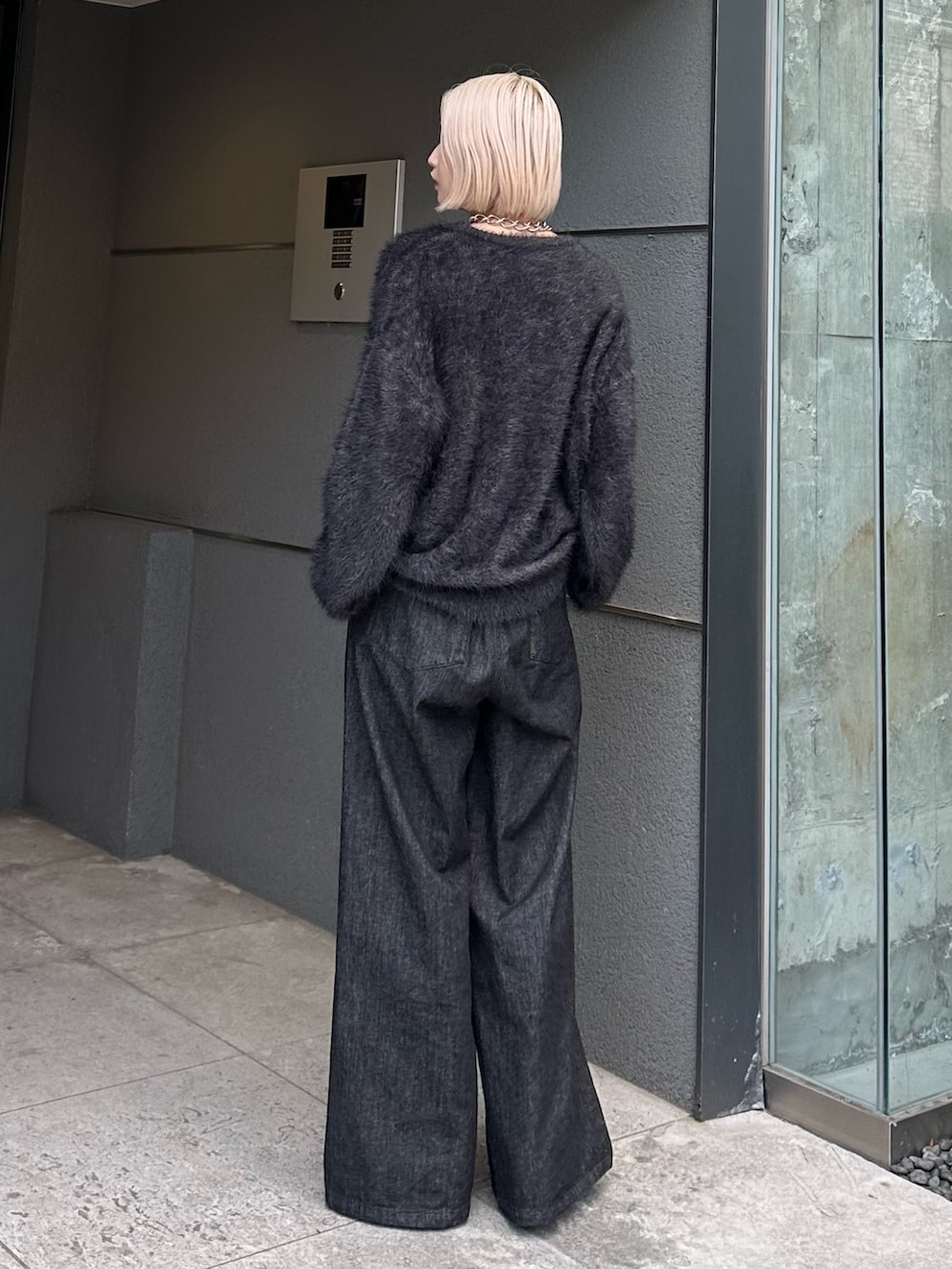 ブラック系のニット/セーター、ブラック系のデニムパンツ、シルバー系のネックレスを着用したレディースの秋コーディネートの4枚目の写真