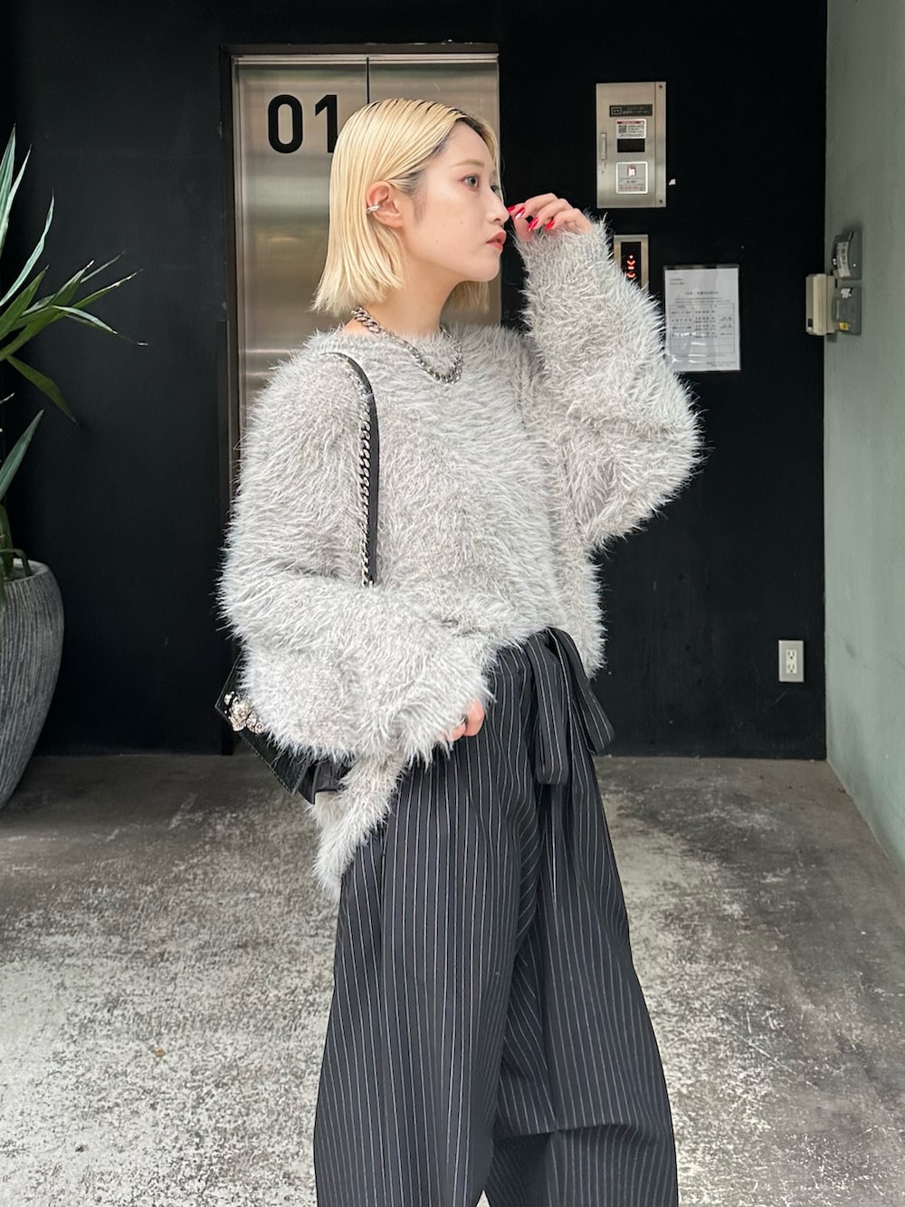 グレー系のニット/セーター、ブラック系のその他パンツ、シルバー系のネックレスを着用したレディースの秋コーディネートの6枚目の写真