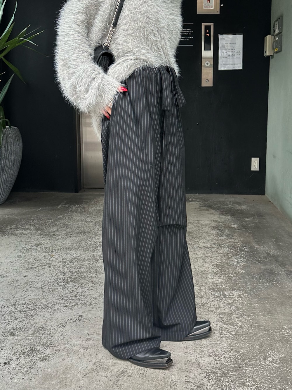 グレー系のニット/セーター、ブラック系のその他パンツ、シルバー系のネックレスを着用したレディースの秋コーディネートの9枚目の写真