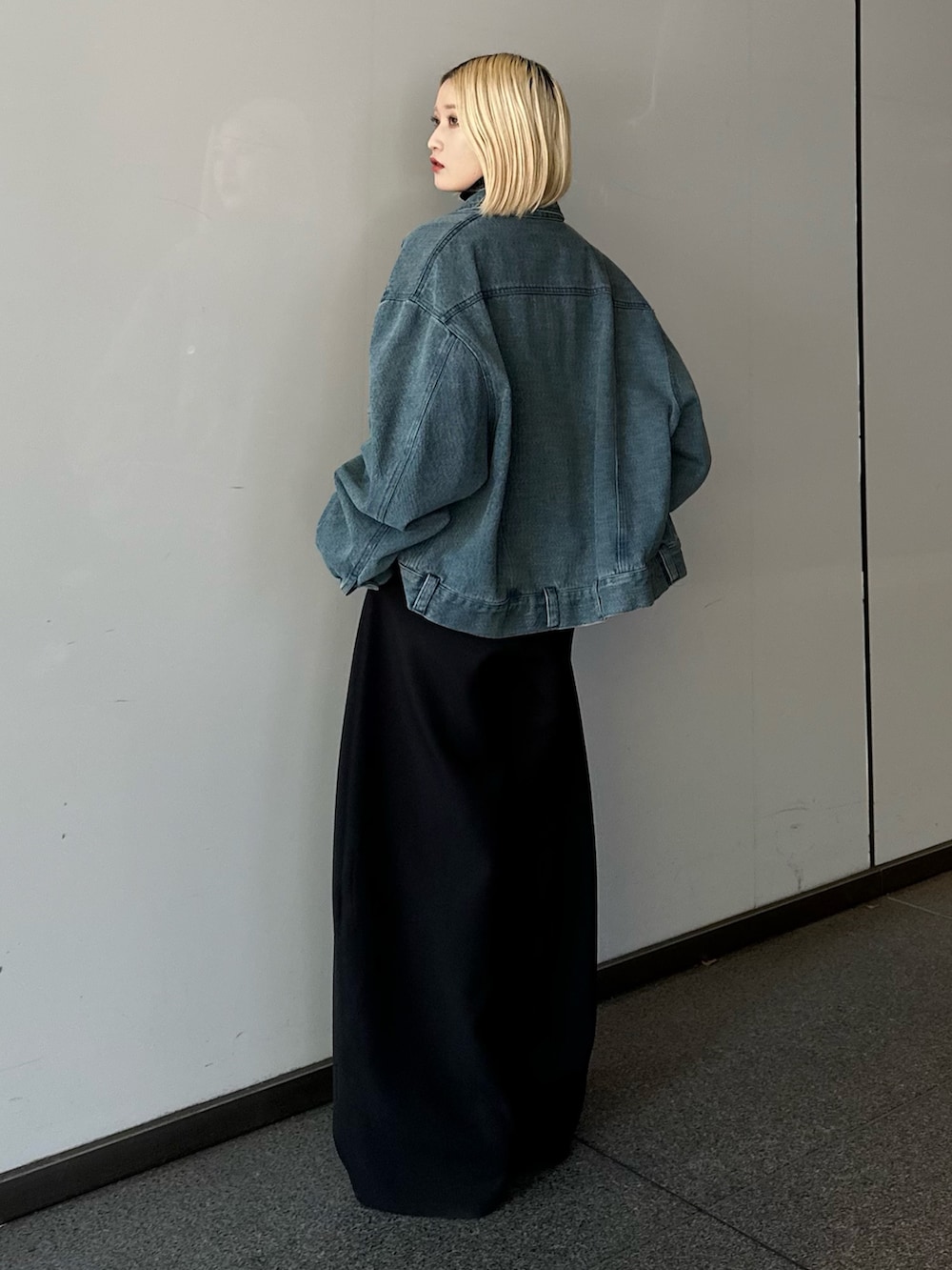 ブルー系のデニムジャケット、ブラック系のニット/セーター、ブラック系のスラックスを着用したレディースの冬コーディネートの3枚目の写真