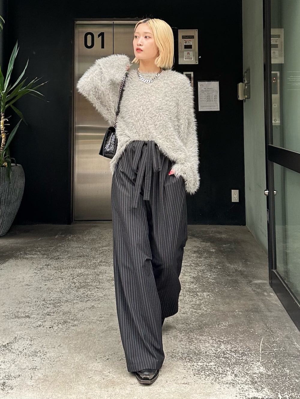 グレー系のニット/セーター、ブラック系のその他パンツ、シルバー系のネックレスを着用したレディースの秋コーディネートの4枚目の写真