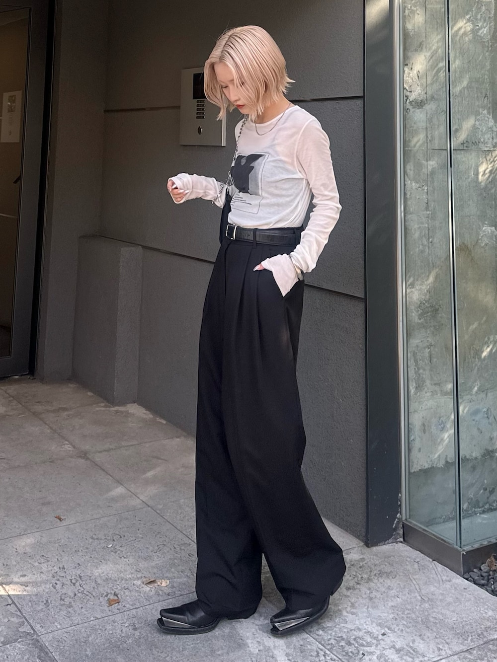 ブラック系のスラックス、ブラック系のショルダーバッグ、ホワイト系のTシャツ/カットソーを着用したレディースの夏コーディネートの2枚目の写真