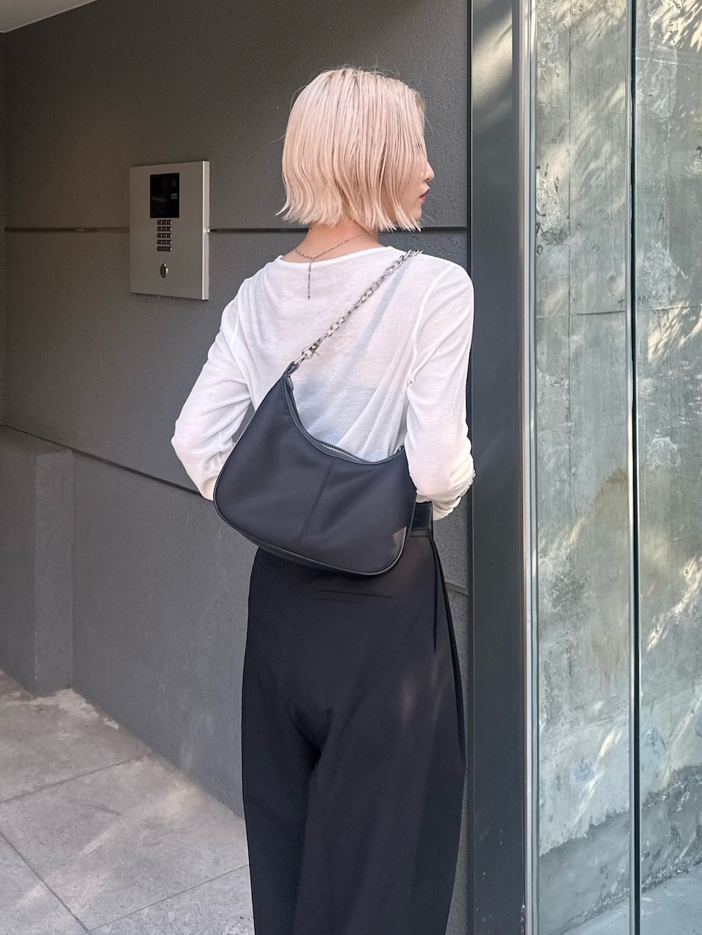 ブラック系のスラックス、ブラック系のショルダーバッグ、ホワイト系のTシャツ/カットソーを着用したレディースの夏コーディネートの6枚目の写真