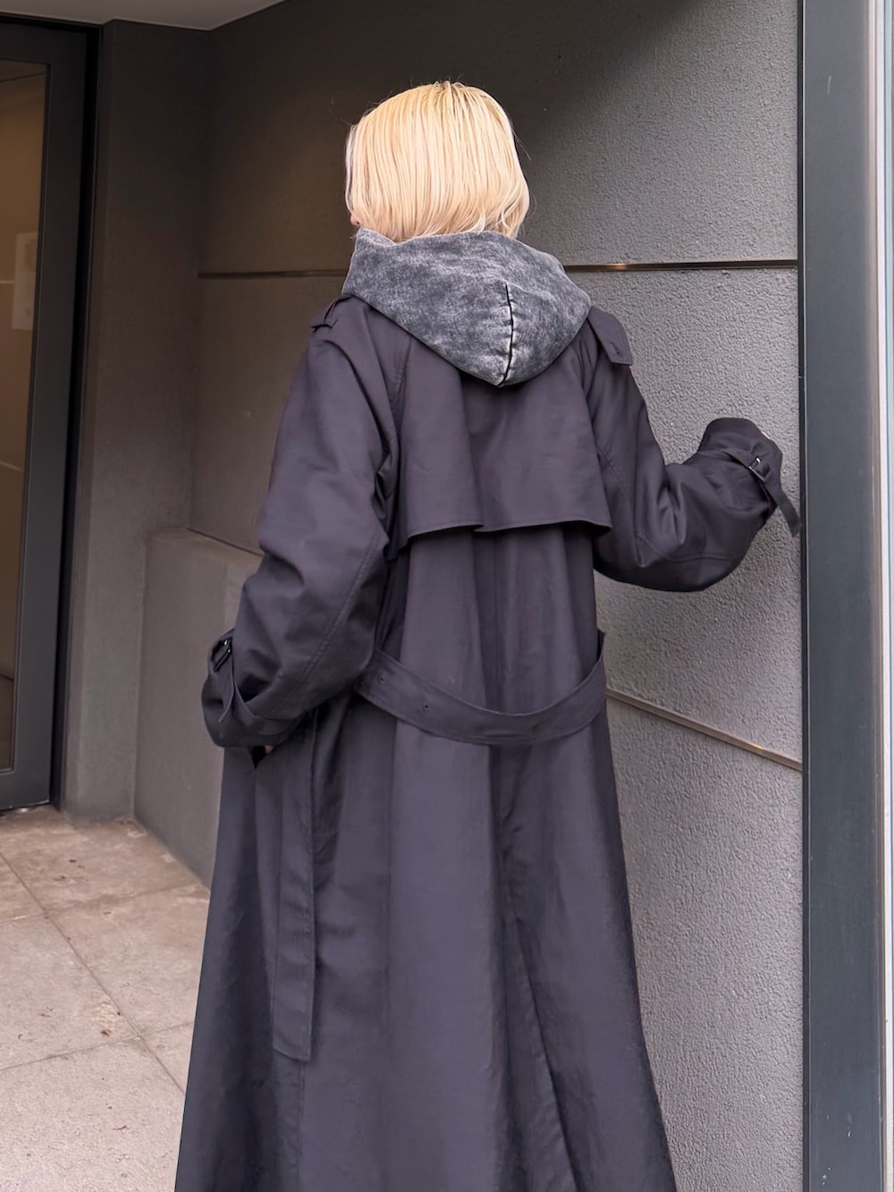ブラック系のパーカー、グレー系のカーゴパンツ、ブラック系のトレンチコートを着用したレディースの秋コーディネートの4枚目の写真