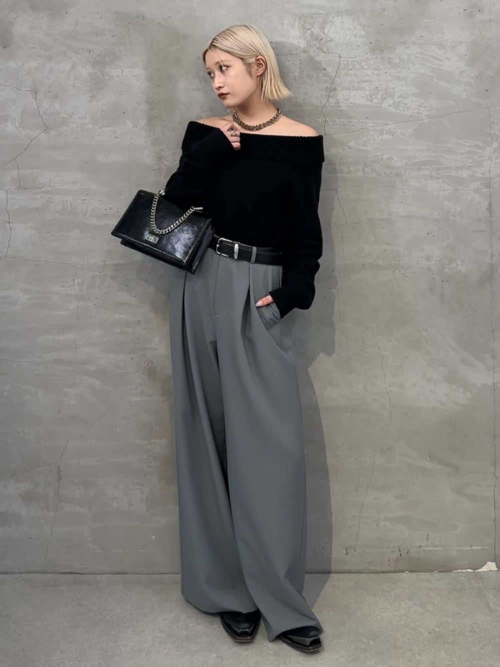 ブラック系のニット/セーター、ブラック系のショルダーバッグ、グレー系のスラックスを着用したレディースの冬コーディネートの2枚目の写真