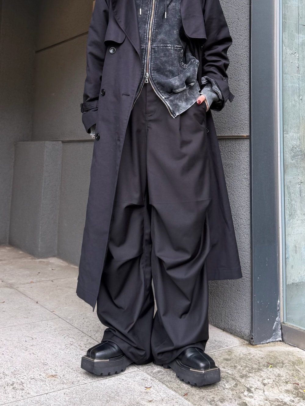 ブラック系のパーカー、グレー系のカーゴパンツ、ブラック系のトレンチコートを着用したレディースの秋コーディネートの5枚目の写真