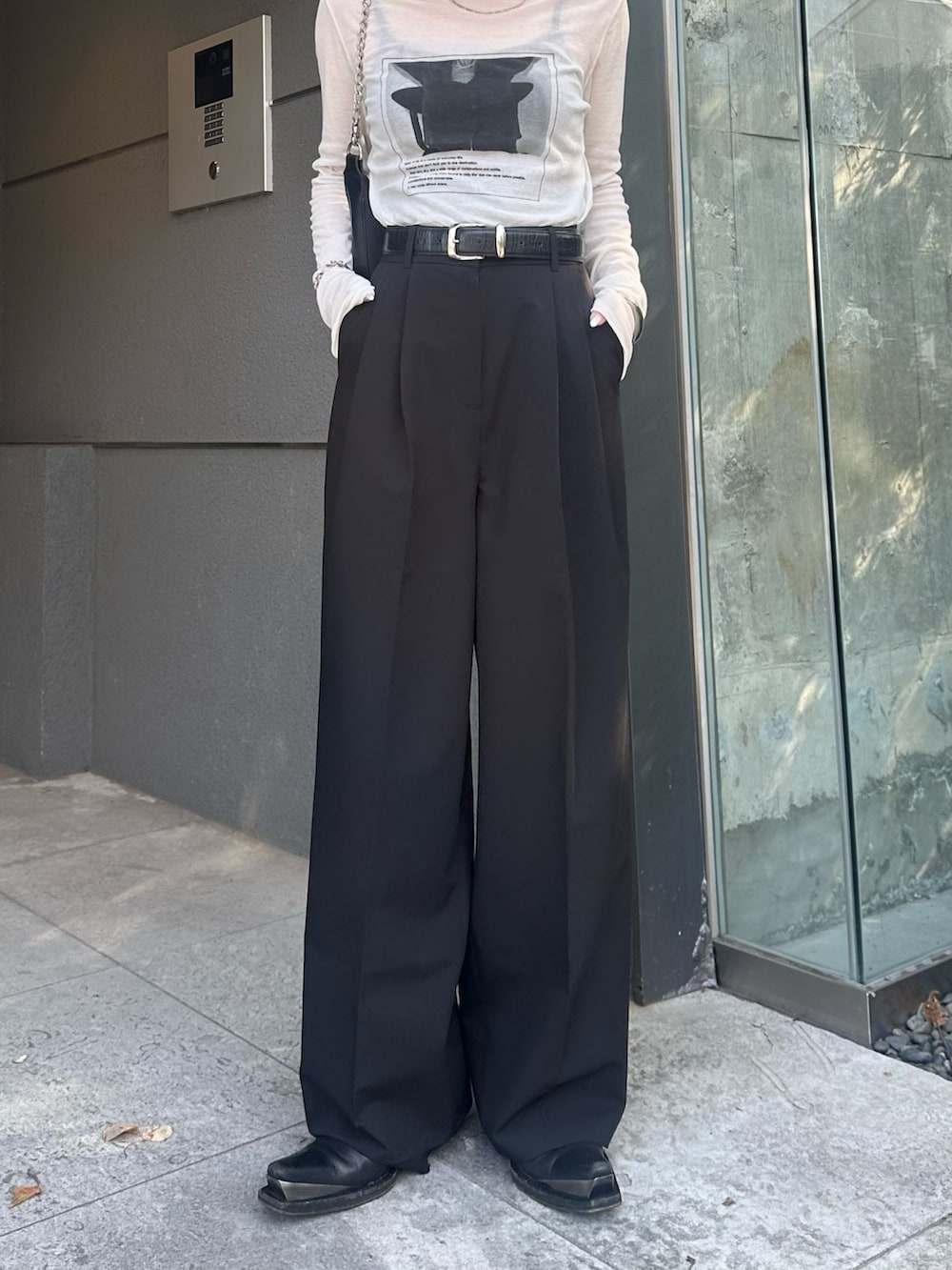 ブラック系のスラックス、ブラック系のショルダーバッグ、ホワイト系のTシャツ/カットソーを着用したレディースの夏コーディネートの8枚目の写真