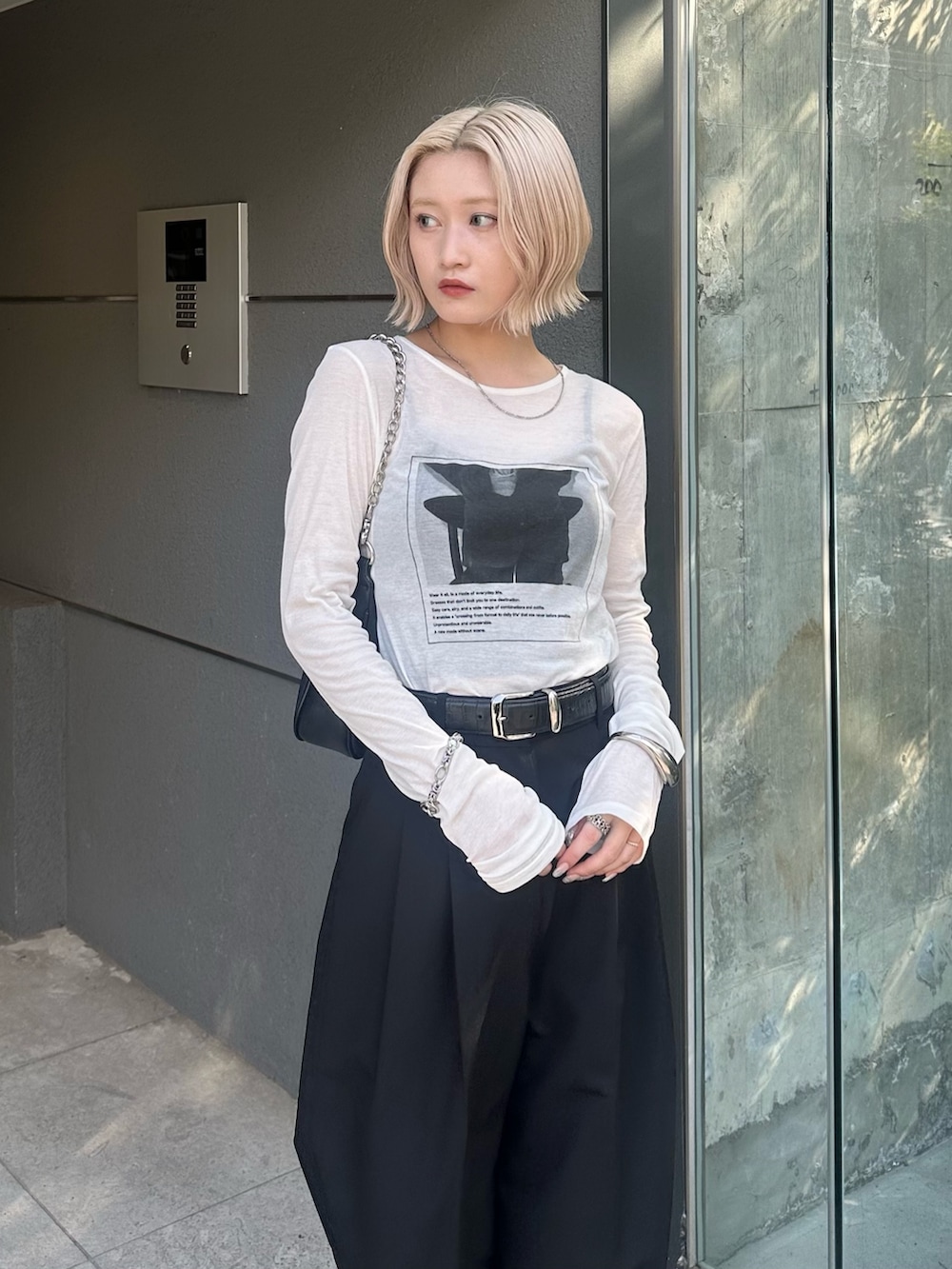 ブラック系のスラックス、ブラック系のショルダーバッグ、ホワイト系のTシャツ/カットソーを着用したレディースの夏コーディネートの5枚目の写真