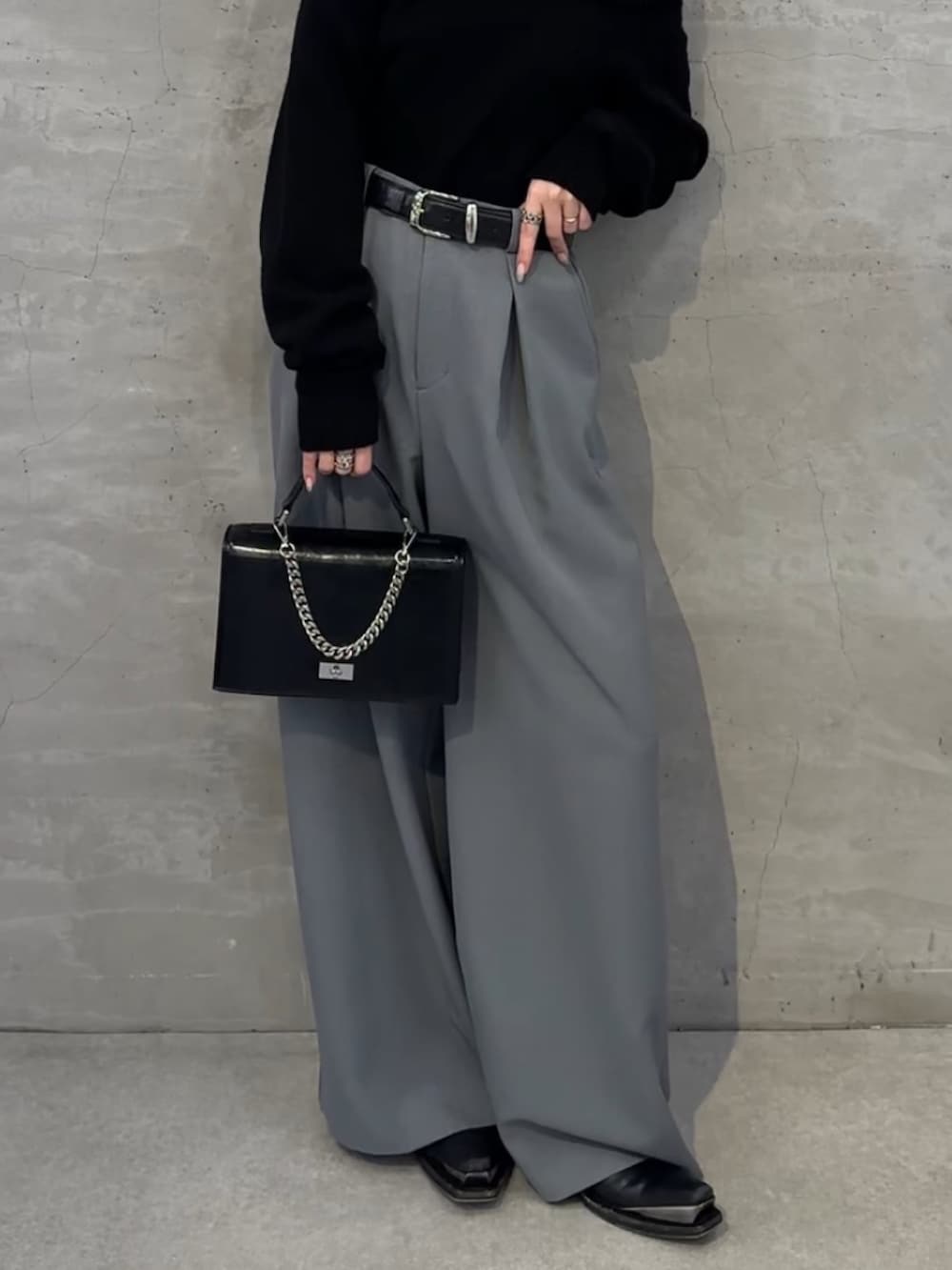 ブラック系のニット/セーター、ブラック系のショルダーバッグ、グレー系のスラックスを着用したレディースの冬コーディネートの4枚目の写真