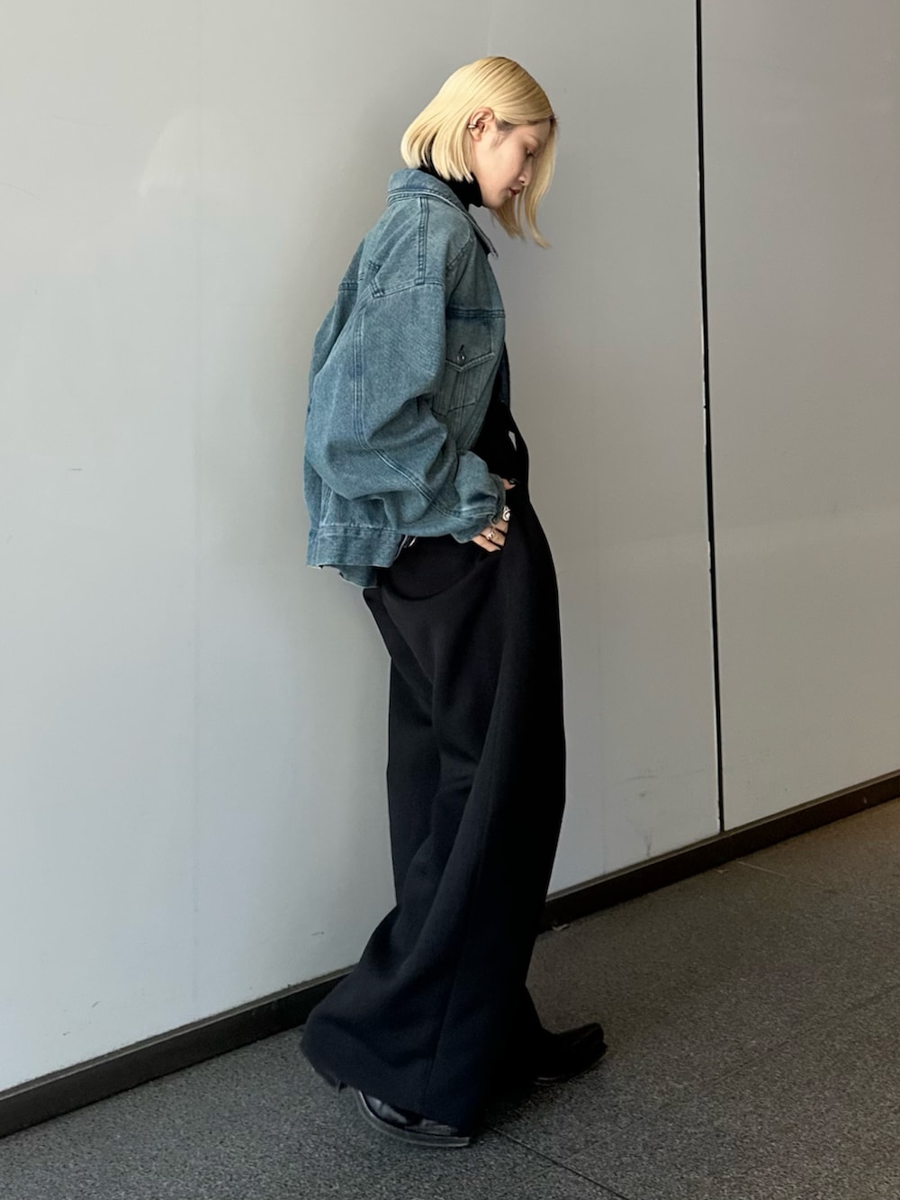 ブルー系のデニムジャケット、ブラック系のニット/セーター、ブラック系のスラックスを着用したレディースの冬コーディネートの2枚目の写真