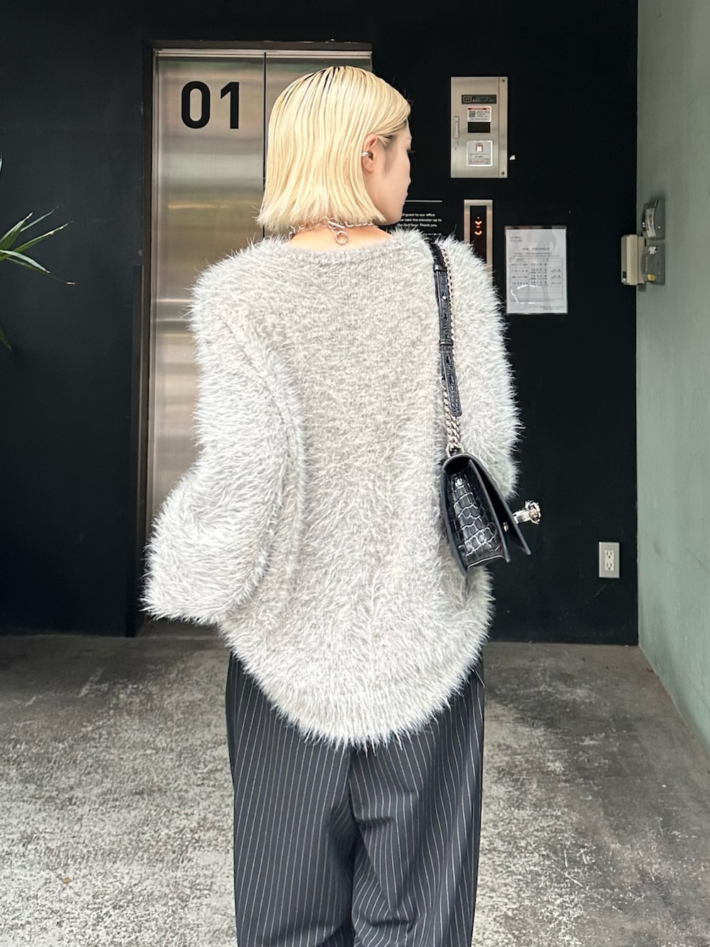 グレー系のニット/セーター、ブラック系のその他パンツ、シルバー系のネックレスを着用したレディースの秋コーディネートの7枚目の写真