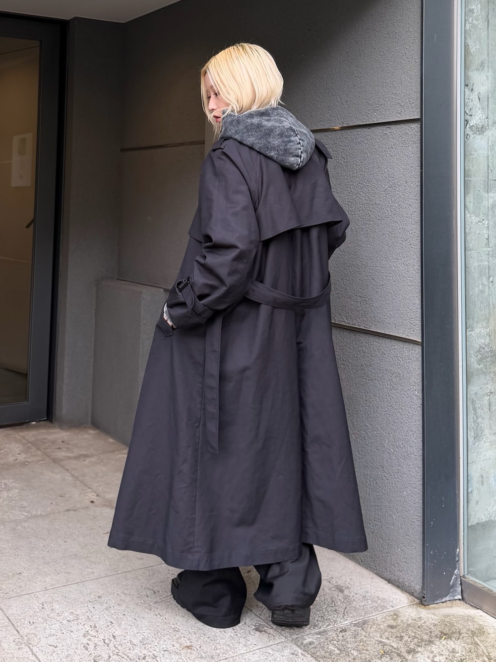 ブラック系のパーカー、グレー系のカーゴパンツ、ブラック系のトレンチコートを着用したレディースの秋コーディネートの2枚目の写真