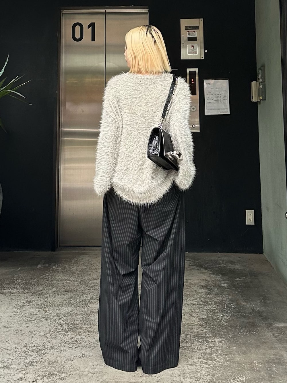 グレー系のニット/セーター、ブラック系のその他パンツ、シルバー系のネックレスを着用したレディースの秋コーディネートの3枚目の写真