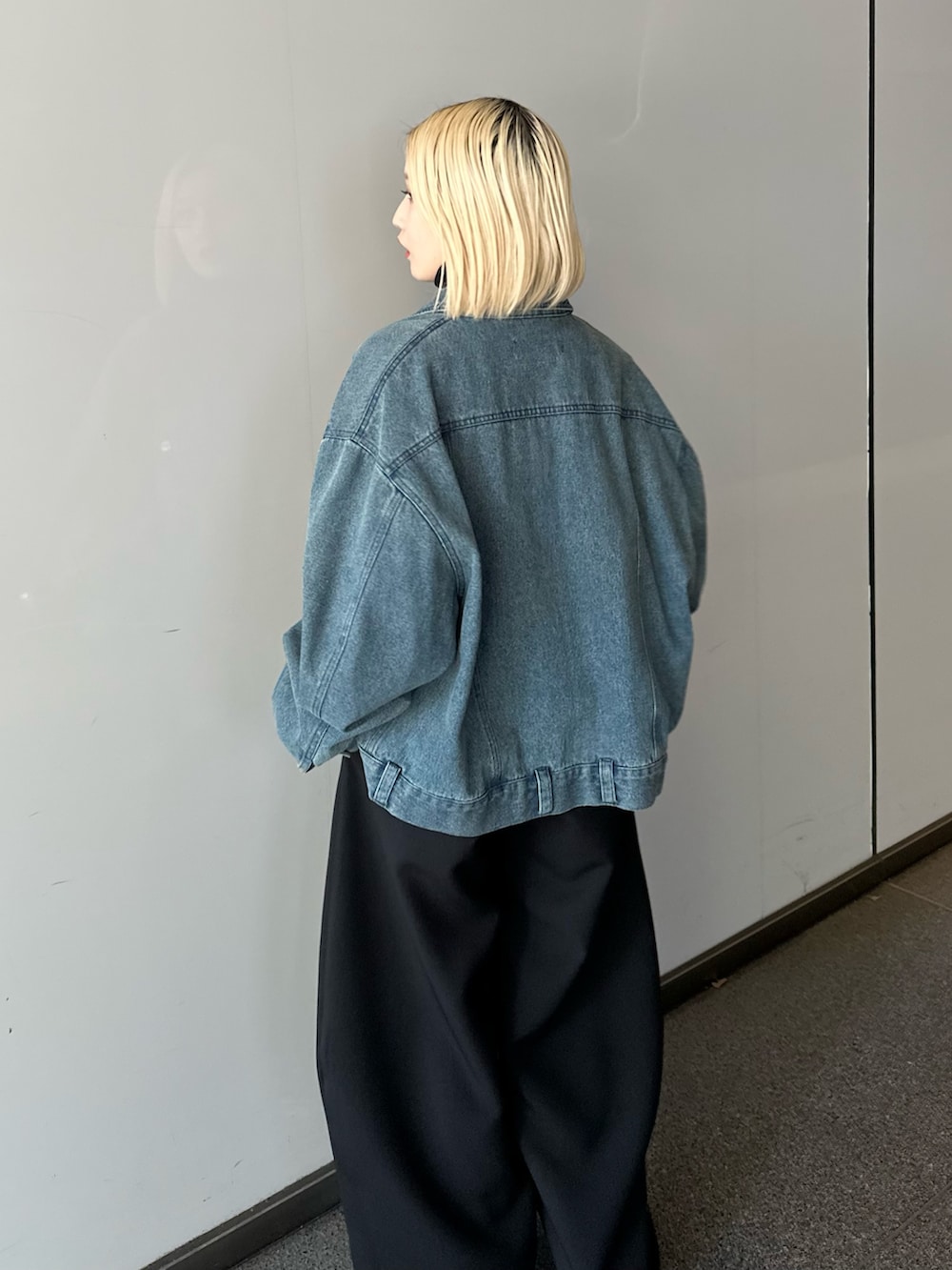 ブルー系のデニムジャケット、ブラック系のニット/セーター、ブラック系のスラックスを着用したレディースの冬コーディネートの5枚目の写真