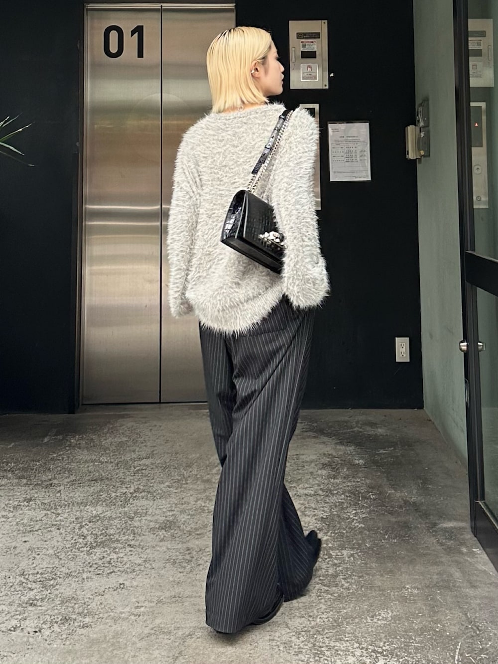 グレー系のニット/セーター、ブラック系のその他パンツ、シルバー系のネックレスを着用したレディースの秋コーディネートの2枚目の写真